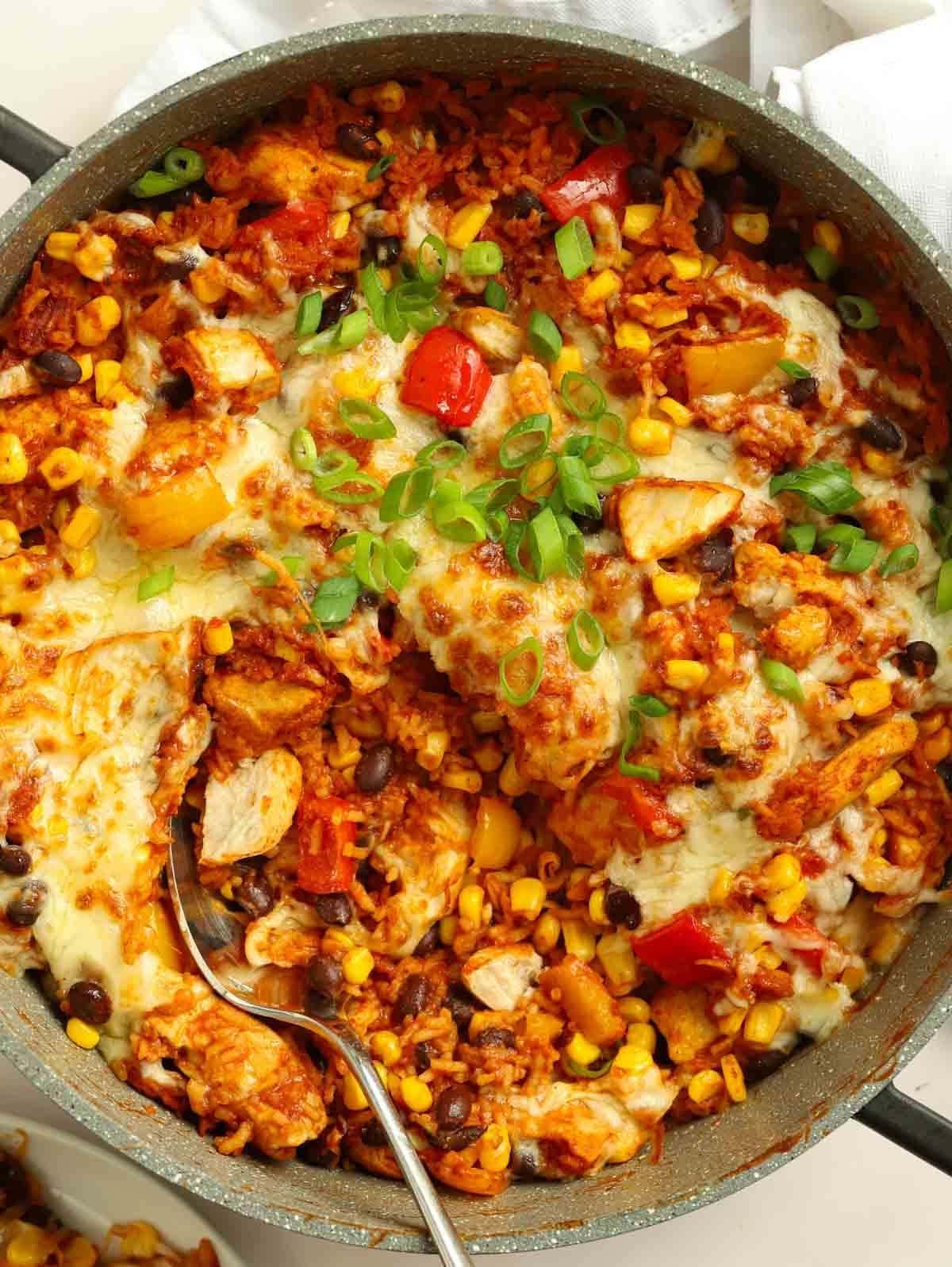 Una grande padella piena di pollo messicano cucinato con riso, peperoni e fagioli. Pronto da mangiare.