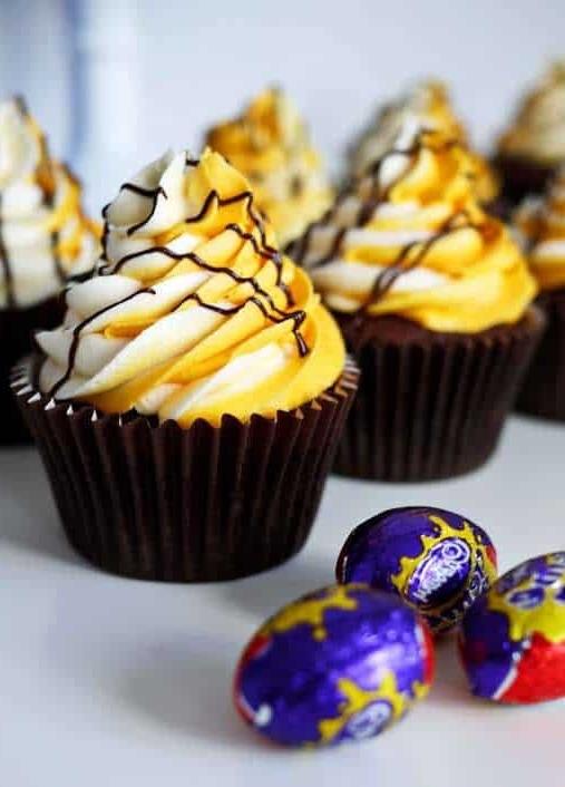 I migliori Cupcakes al Creme Egg 2 Una fila di Cupcakes Cadbury's Creme Egg con mini Creme Egg in carta stagnola a lato.