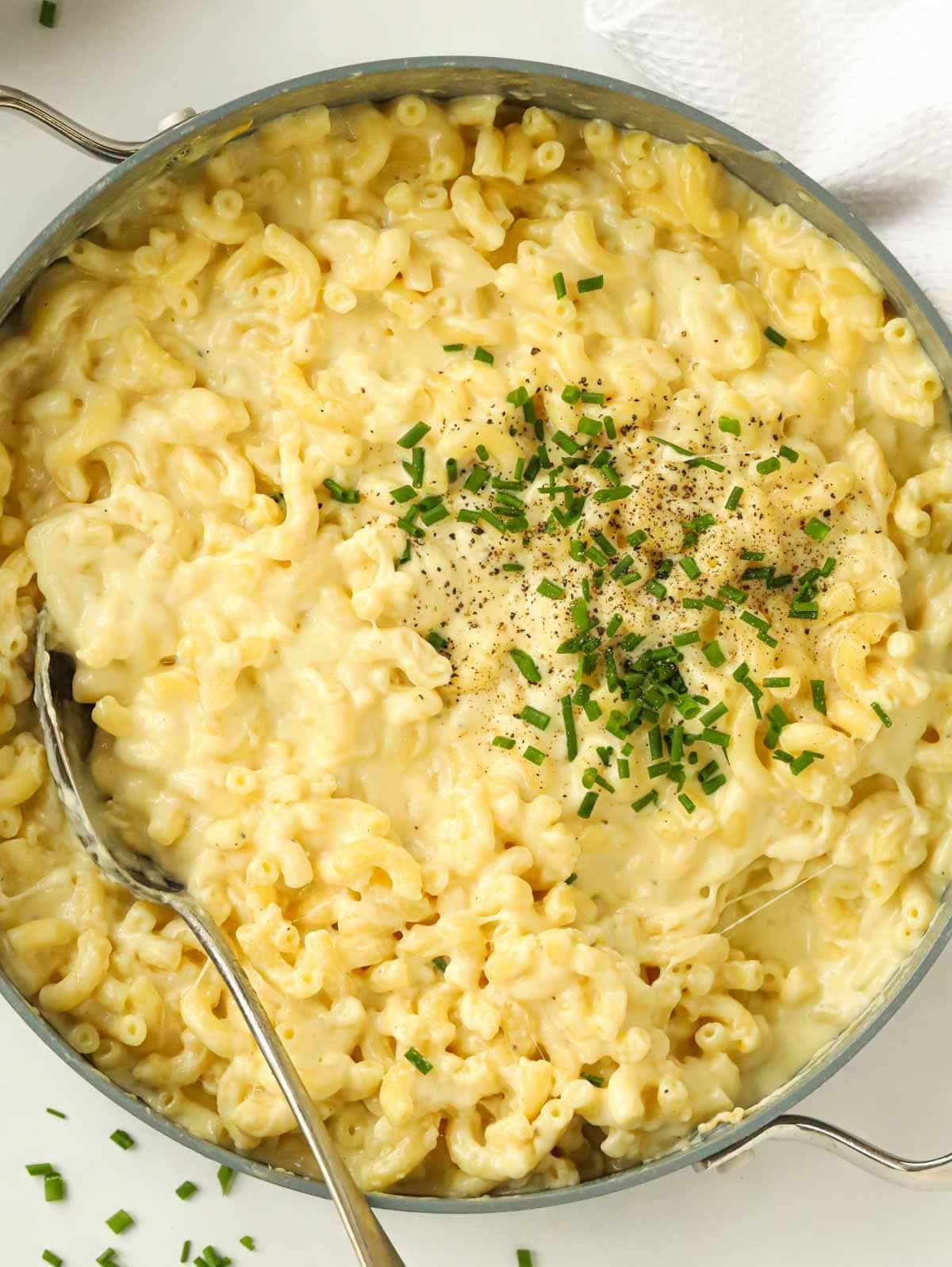 Una grande pentola piena di Maccheroni al Formaggio cotti e semplici, guarniti con erba cipollina.
