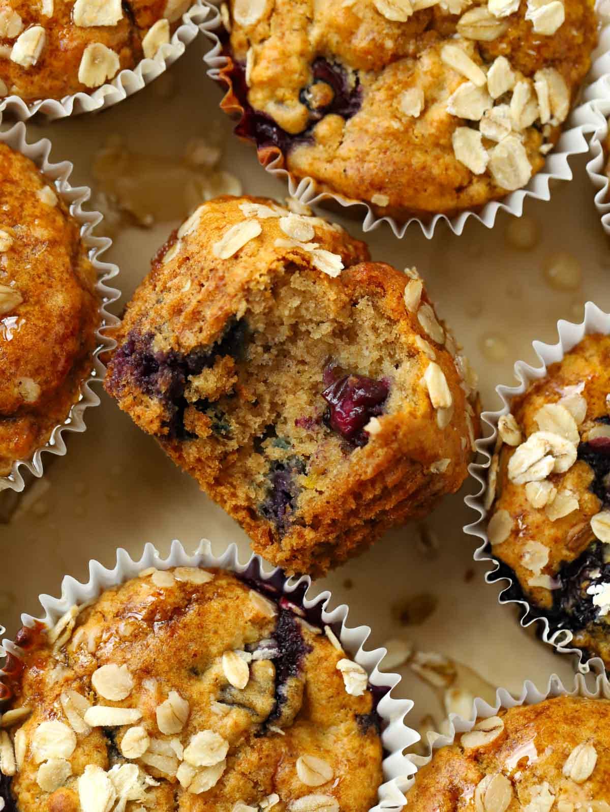 Primo piano di un muffin salutare per la colazione su un vassoio di altri muffin con ripieno di mirtilli.