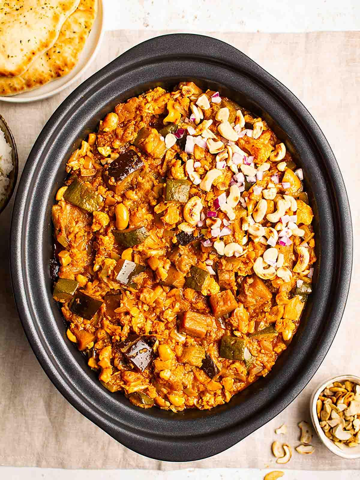 Vegetarian slow cooker curry in a slow cooker topped with cashew nuts.