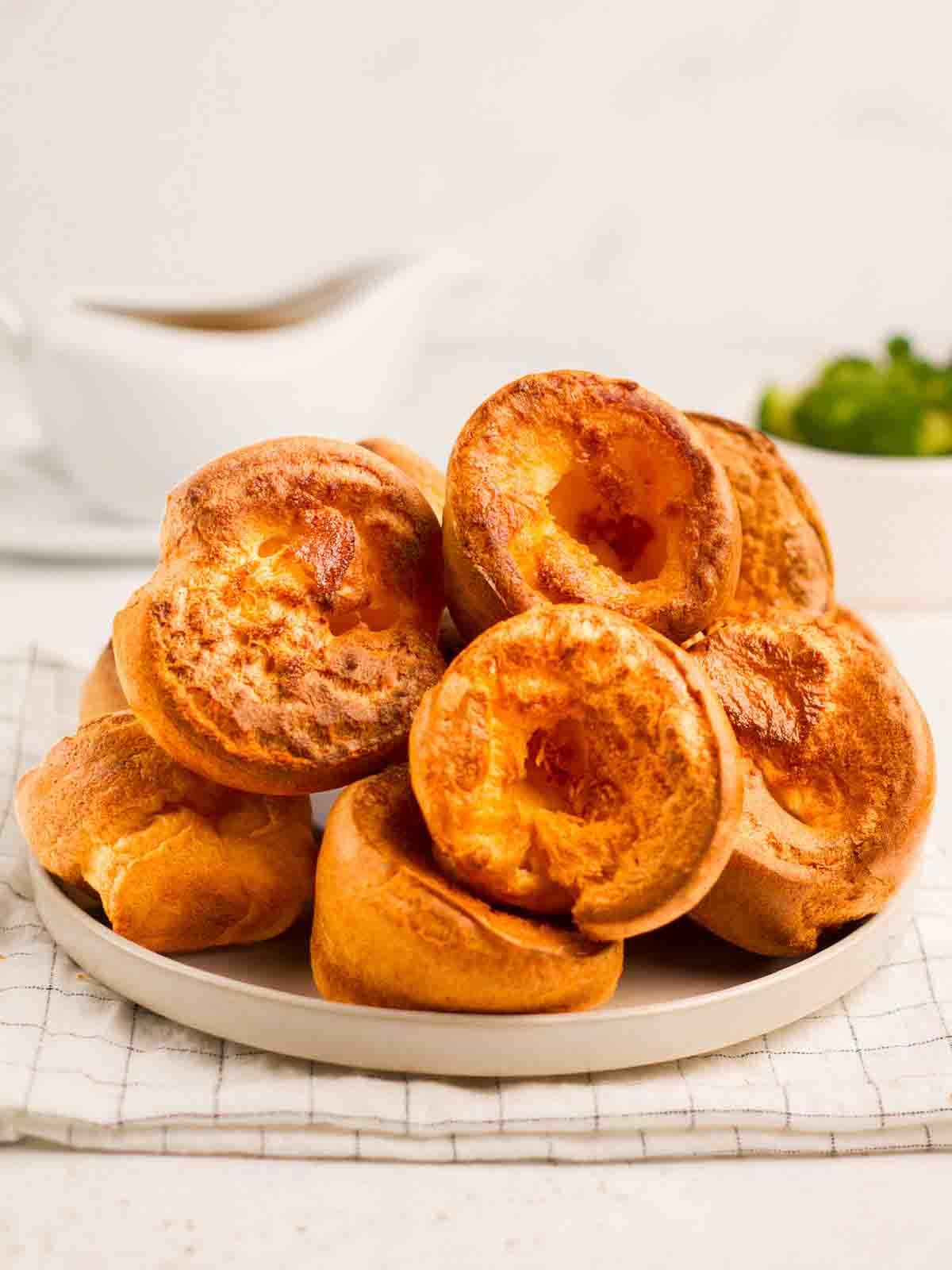 Yorkshire Puddings {Ricetta infallibile!} 2 Un piatto pieno di una pila di Pudding dello Yorkshire dorati e gonfi.