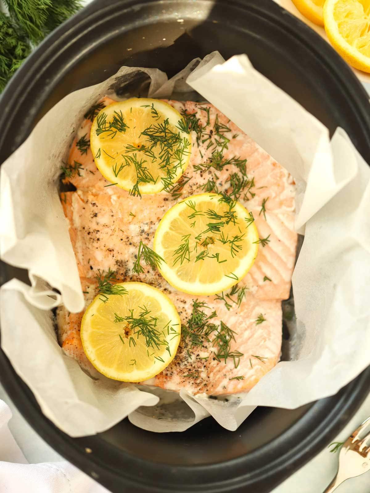 Semplice Salmone in Slow Cooker 2 Un trancio di salmone cotto nella slow cooker, avvolto nella carta da forno con limone sopra.