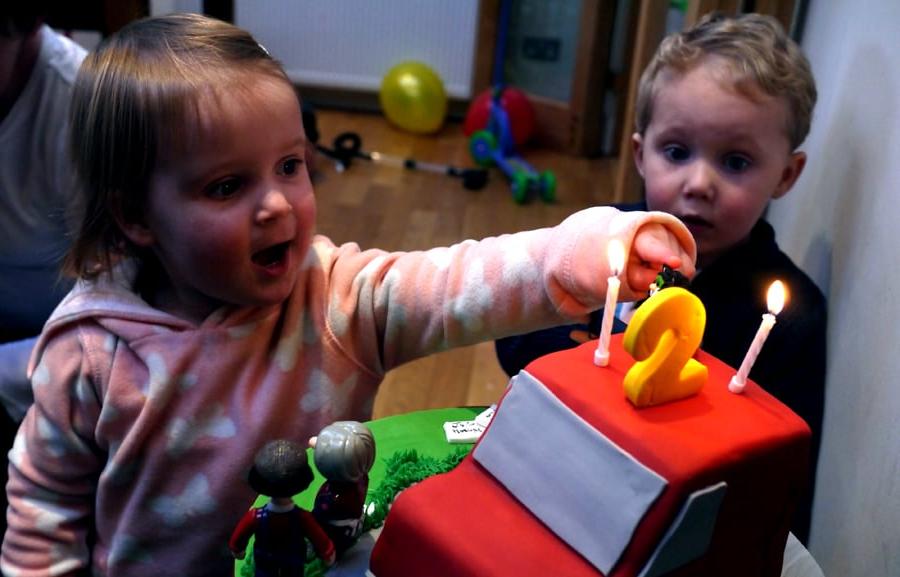 Bambini eccitati davanti alla torta di compleanno a tema furgone di Postman Pat