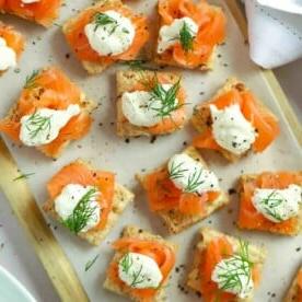 Menù di San Valentino o delle Amiche 3 Cibo da festa perfetto su un tagliere. Tartine al Salmone Affumicato guarnite con crème fraîche e aneto.