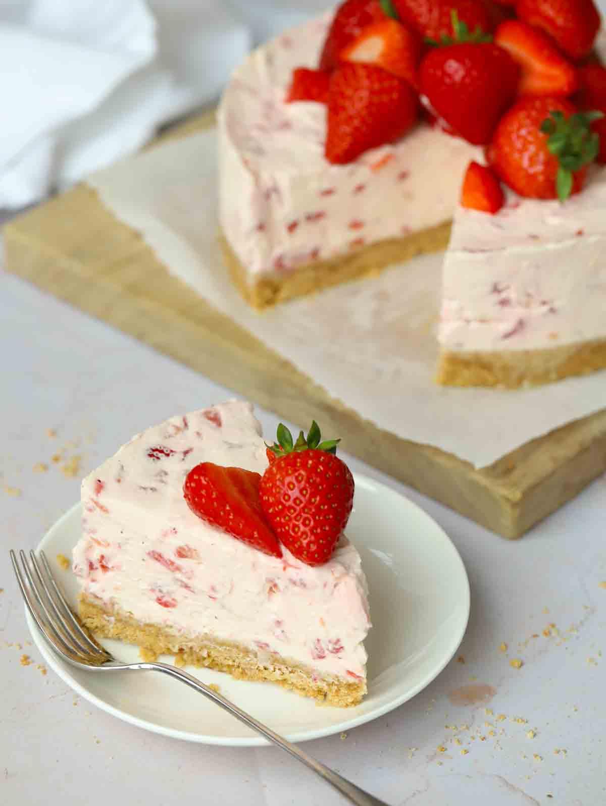 Una fetta di cheesecake alle fragole su un piattino, con una forchetta accanto, pronta per essere gustata.