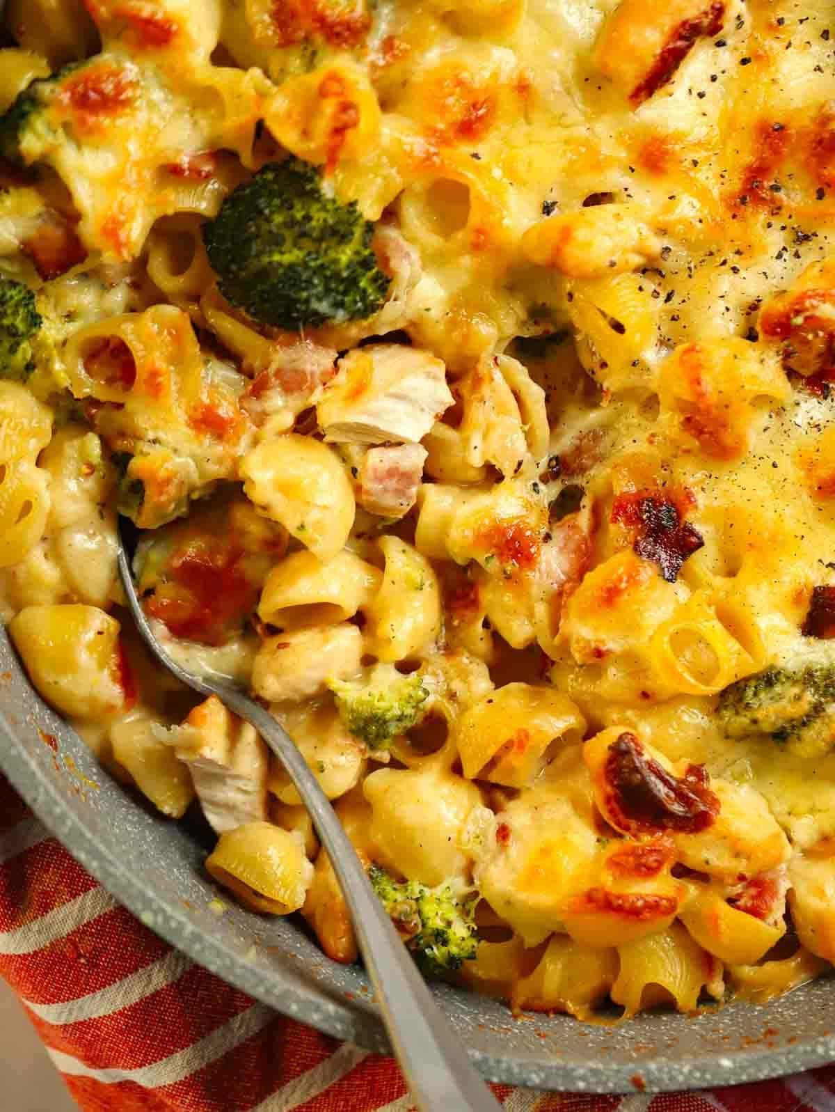 Pasta al Forno con Pollo e Pancetta {Così Facile!} 3 Vista a volo d'uccello di un angolo di una teglia piena di Pasta al Forno con Pollo, con un cucchiaio infilato, pronta per essere servita.
