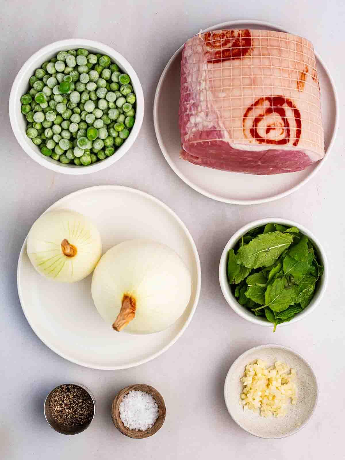 Gli ingredienti crudi per la Zuppa di Piselli e Prosciutto disposti su un piano in ciotole.