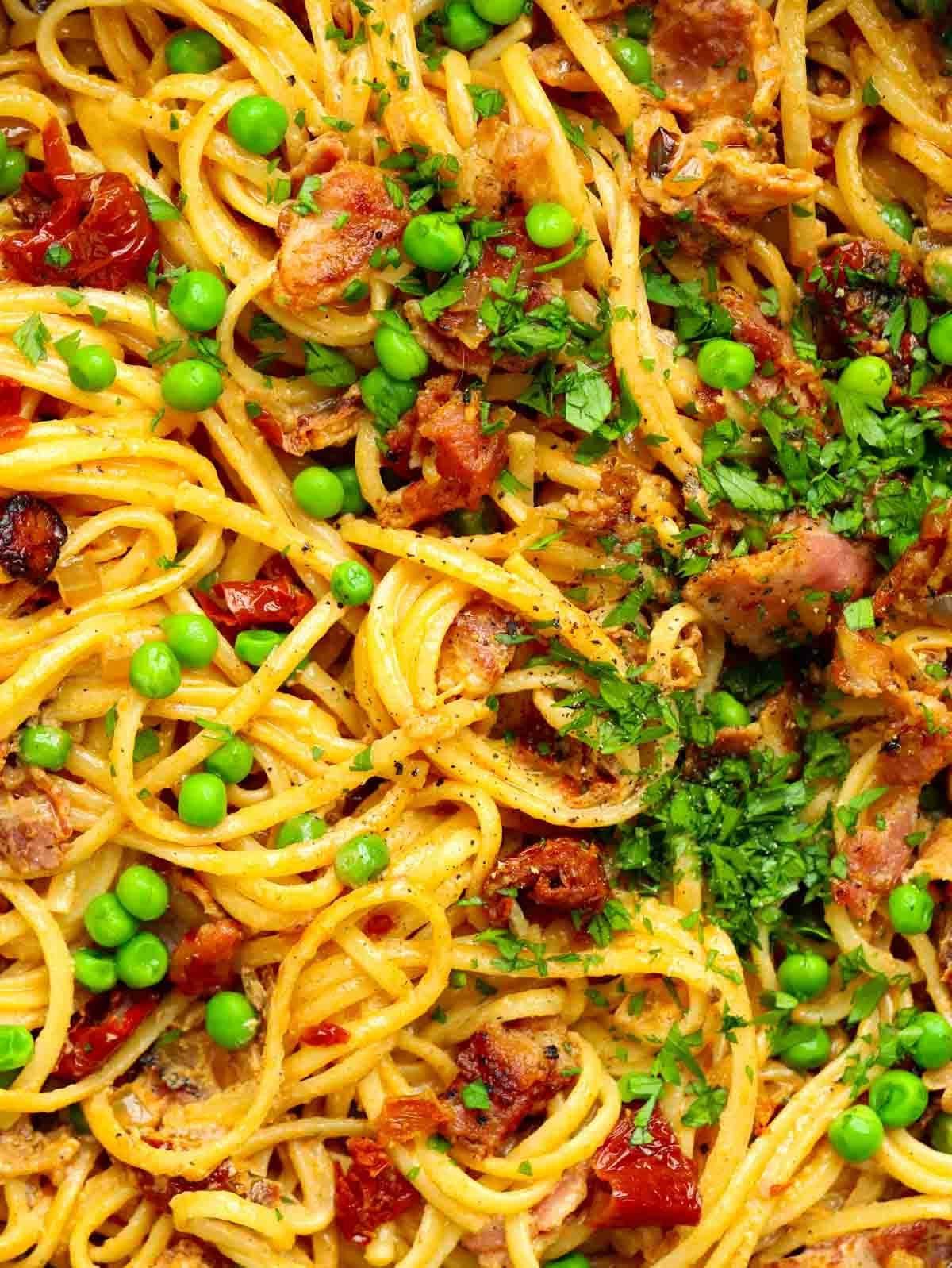 Un misto di pancetta, piselli e spaghetti pronti da gustare.