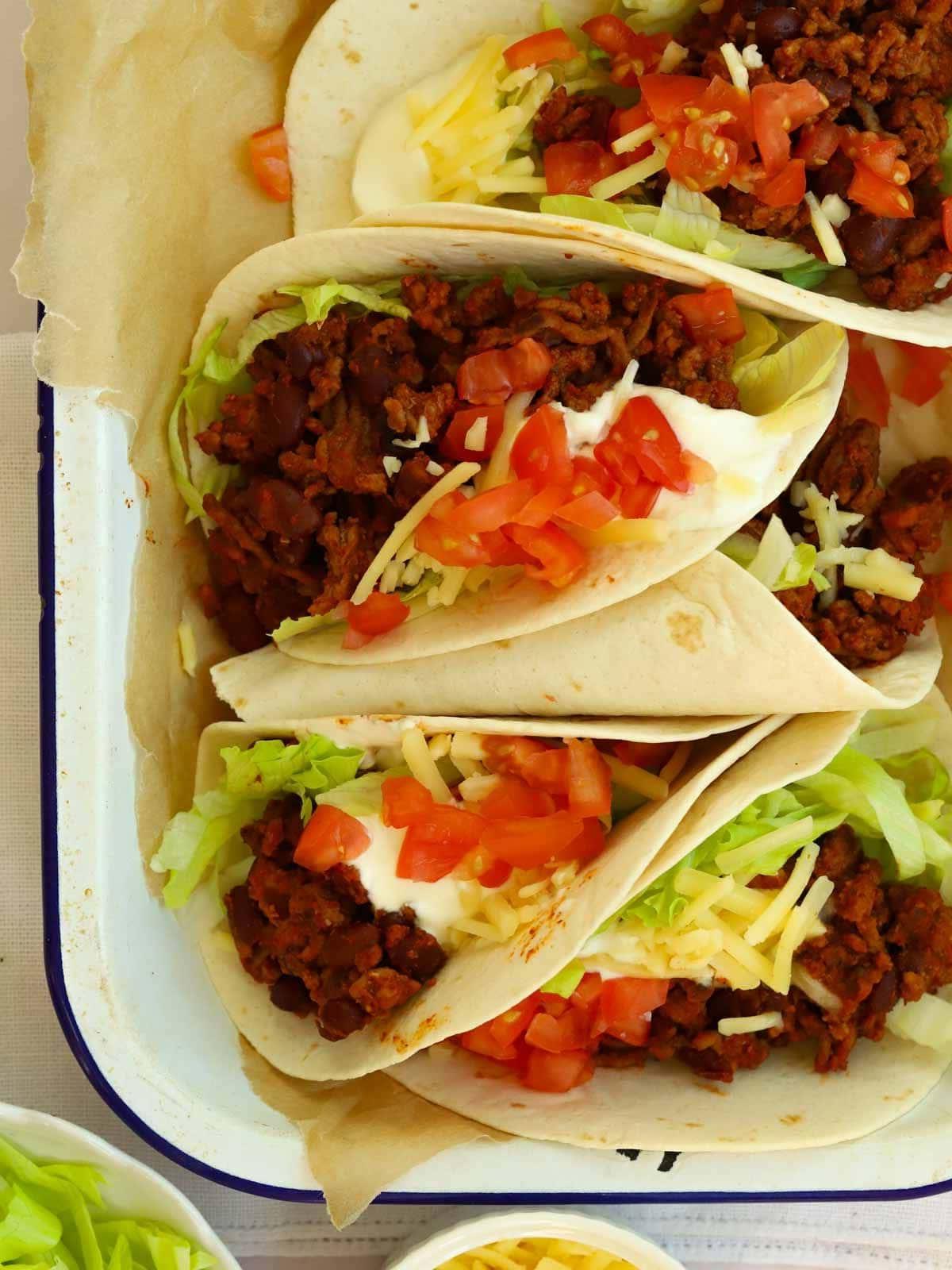 Tacos di Manzo Facili {Pronto in 15 Minuti} 3 Una teglia piena di tacos di manzo ripieni di insalata fresca e condimenti.