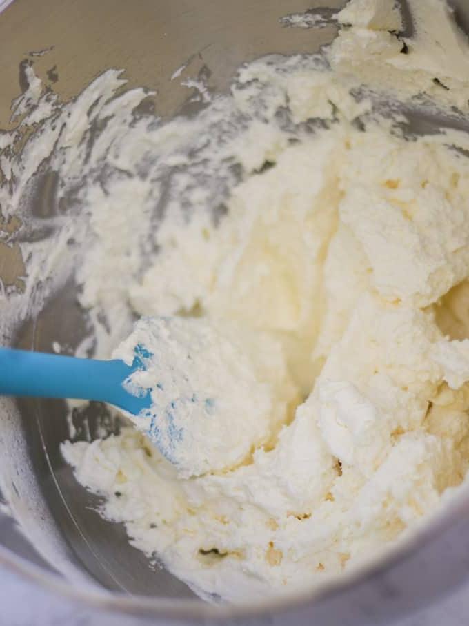 Ciotola d'argento con panna montata e una spatola blu.