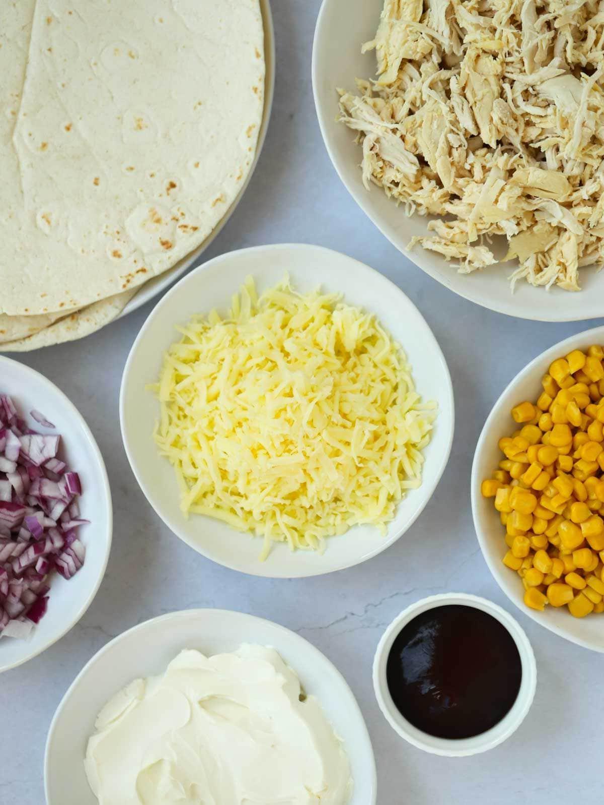 Facili Wrap di Pollo 4 Gli ingredienti per i wraps di pollo disposti in ciotole su un piano di lavoro.