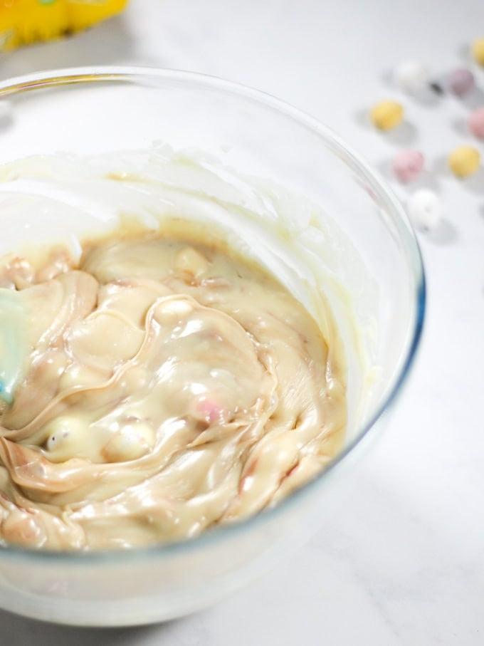 Impasto di fudge alle Mini Uova in una ciotola di vetro, non ancora solidificato per il passaggio 2 del processo.