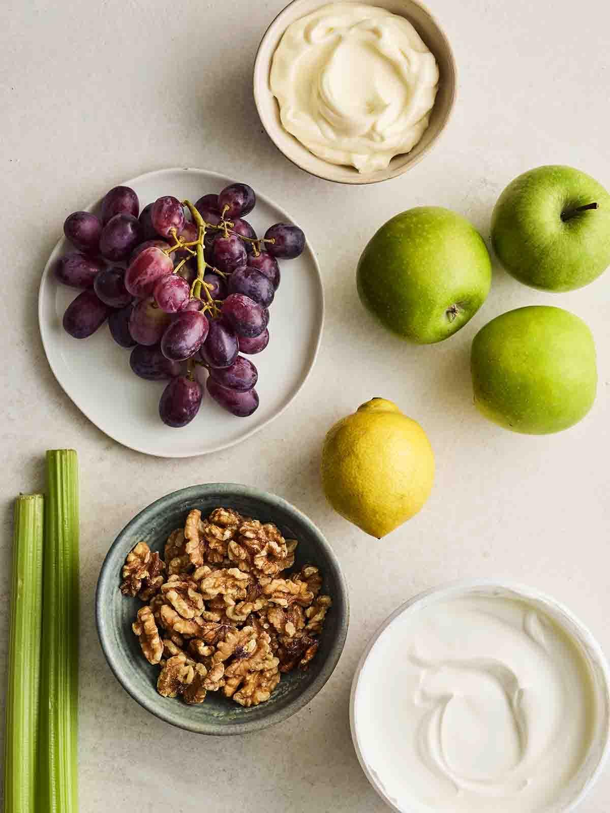 Gli ingredienti per preparare un'Insalata Waldorf disposti su un piano di lavoro.