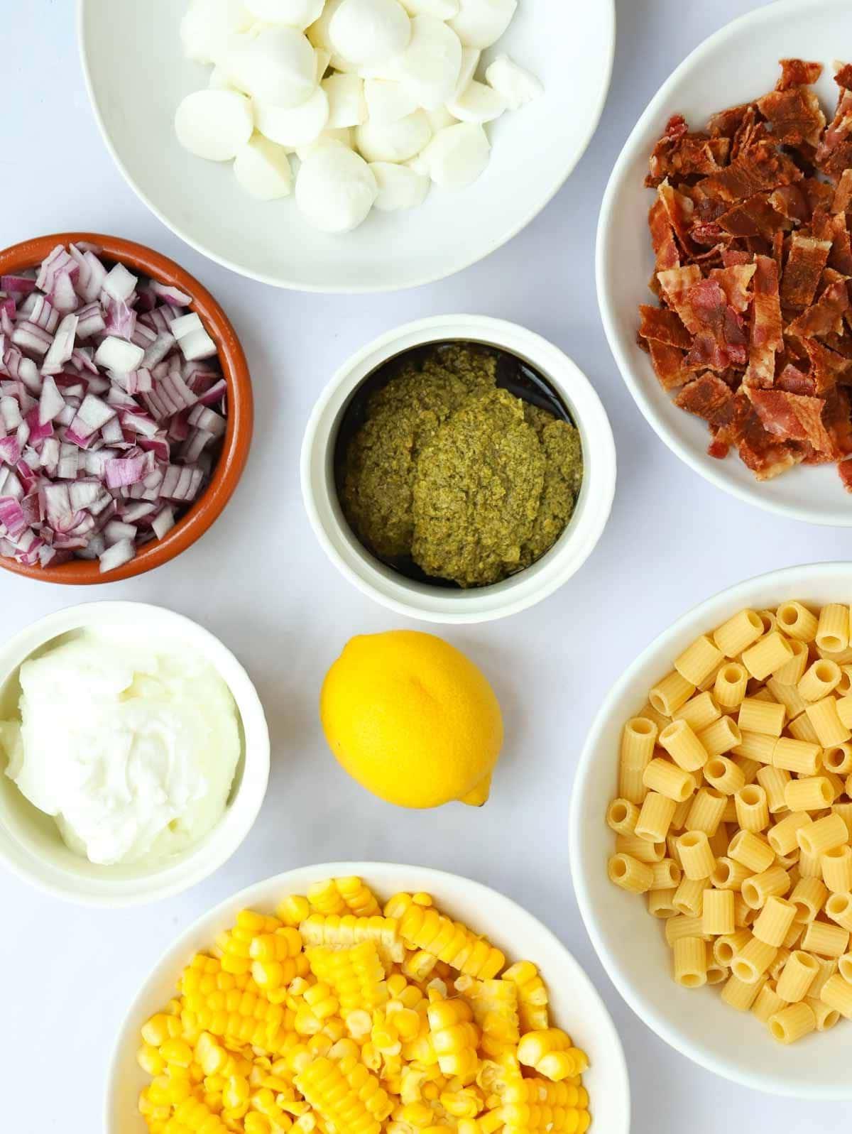 La Migliore Insalata di Pasta al Pesto di Sempre {Pronta in 15 Minuti} 4 Ingredienti per un'insalata di pasta al pesto disposti su un piano di lavoro bianco.