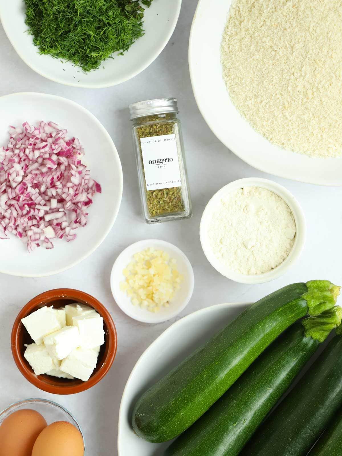 Gli ingredienti per fare le frittelle di zucchine disposti su un piano di lavoro.