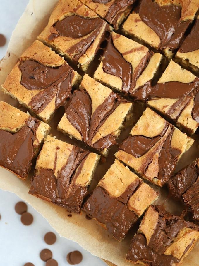 Immagine dall'alto di blondies al burro d'arachidi con vortici di Nutella su carta marrone con sfondo bianco