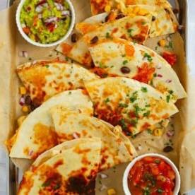 Ricette in 15 minuti {Settimana 4} 4 Quesadillas di pollo tagliate a quarti su una teglia con salse.
