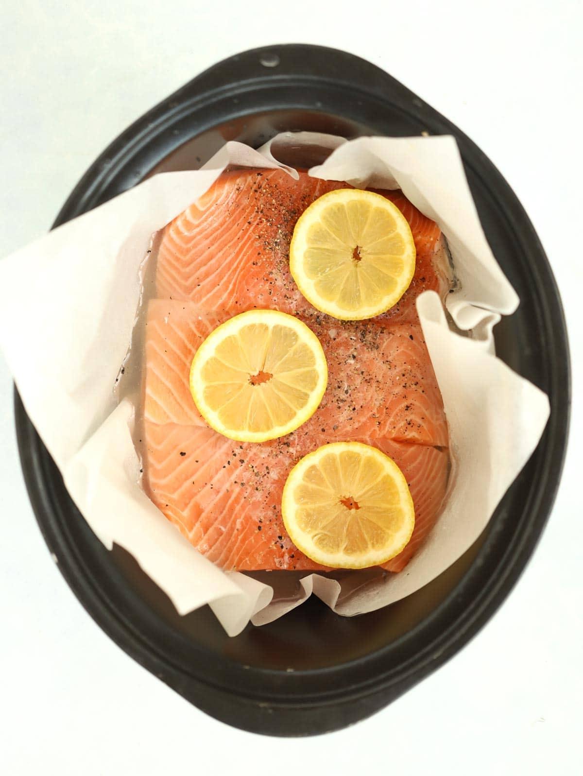 Semplice Salmone in Slow Cooker 4 Filetti di salmone crudo in una slow cooker con limone sopra per la ricetta Salmone al Slow Cooker.