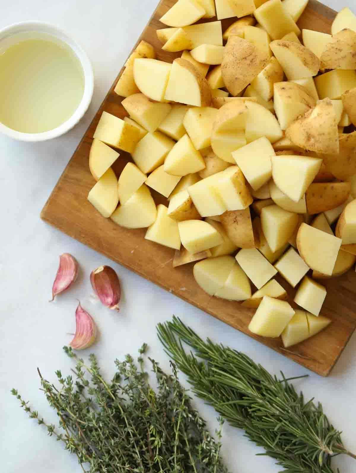 Patate Parmentier all'aglio e alle erbe aromatiche 4 Gli ingredienti crudi per le patate Parmentier: cubetti di patate, olio, spicchi d'aglio ed erbe fresche.