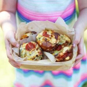 **Ricetta Mini Quiche Senza Crosta** 4 Un cestino per il pranzo pieno di mini quiche senza crosta, tenuto nelle mani di una bambina, pronta per gustare il suo pasto sano e delizioso.