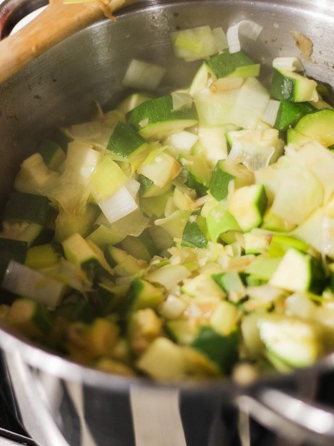 Zuppa Facile di Zucchine al Parmigiano 5 Cubetti di zucchina che cuociono in una padella con cipolle tritate per la ricetta della vellutata di zucchine.