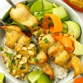 Piano Pasti 7 5 Una ciotola di spiedini di pollo satay con contorno di insalata fresca e riso, guarniti con arachidi tritate per un pasto completo.