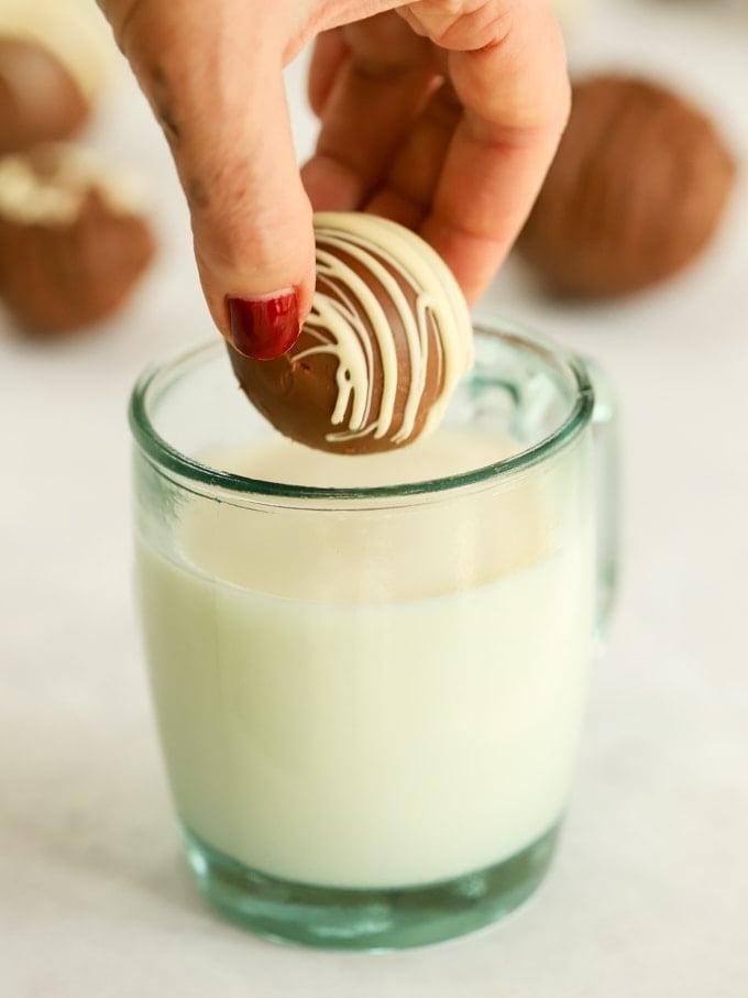 Bombe di Cioccolata Calda {Ricetta Facile} 5 Tazza di latte caldo che fa cacao con una bomba di cioccolata pronta per essere inserita da una mano.