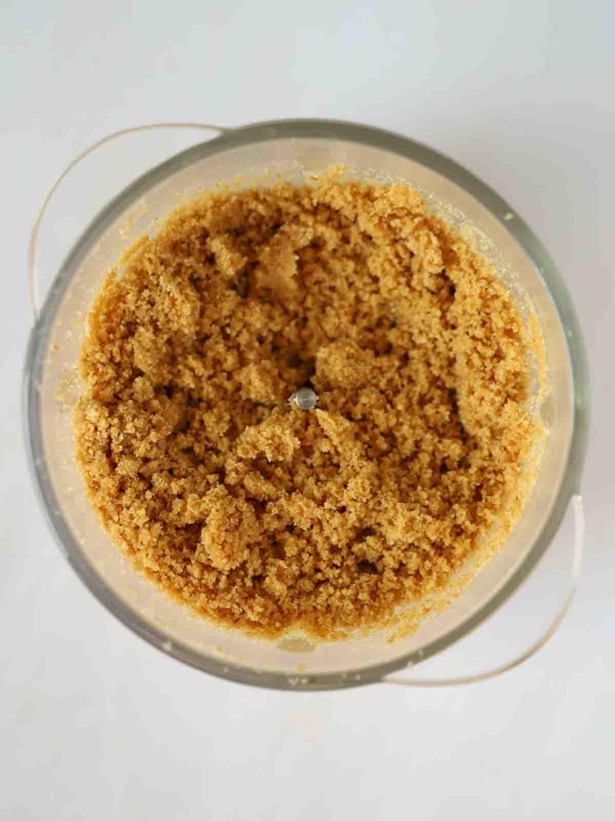 Biscotti tritati in un robot da cucina per il passaggio 1 della ricetta della Cheesecake alle Fragole.