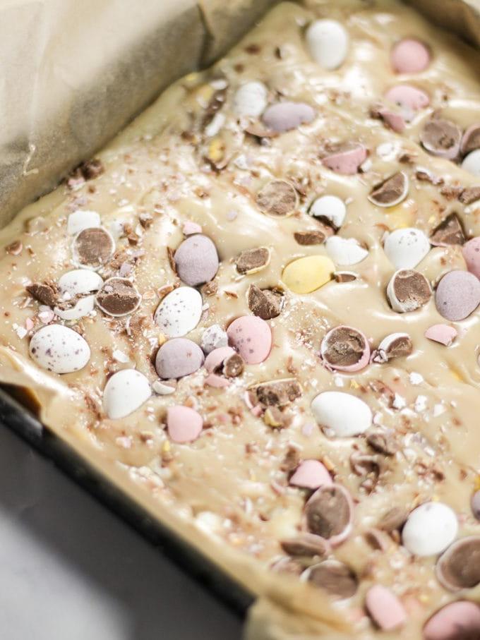 Impasto di fudge alle Mini Uova in una teglia metallica nera prima di andare in frigo.