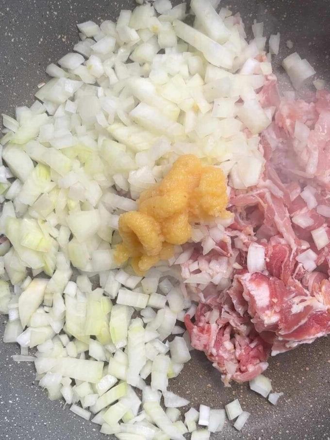 Cipolle, pancetta e aglio in una padella che friggono per la ricetta della Pasta con Pancetta. Passaggio 1.