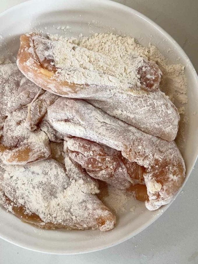Petti di pollo infarinati prima di essere cotti per la ricetta Pollo Sposami. Passaggio 1.