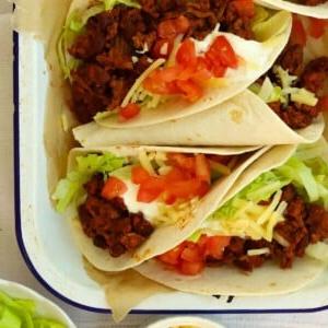 Tacos di Manzo Facili {Pronto in 15 Minuti} 5 Tacos ripieni di manzo con insalata e formaggio sopra.