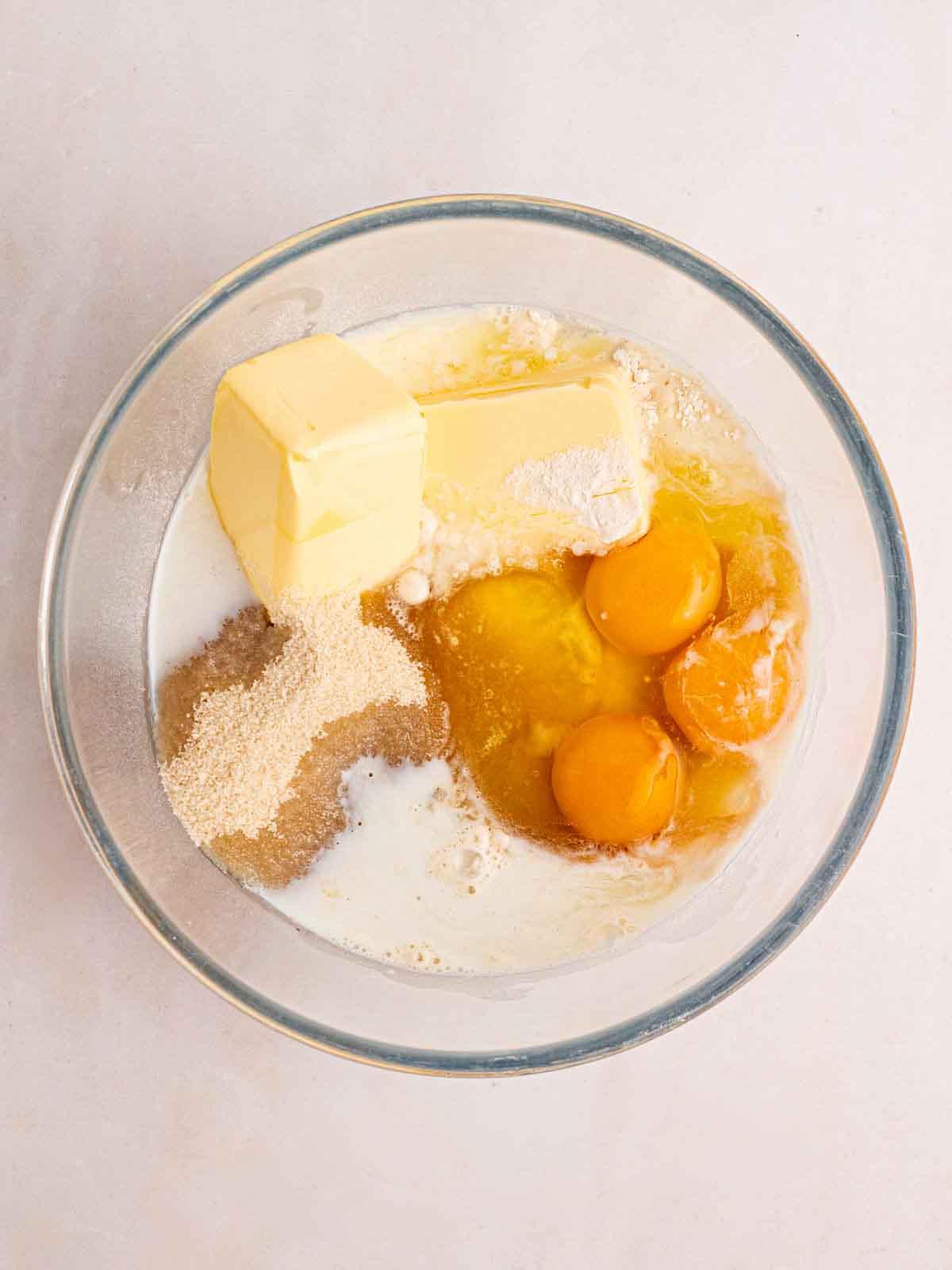 Torta Scolastica {Ricetta Facile!} 5 Burro, uova, latte e zucchero in una ciotola di vetro pronti per essere mescolati per fare una torta.