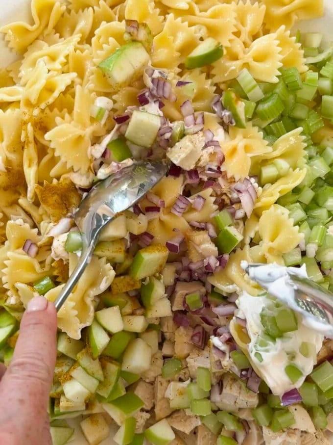 Insalata di Pasta al Pollo {Pasto da 15 Minuti} 5 Due cucchiai mescolano gli ingredienti per un'insalata di pasta con pollo.