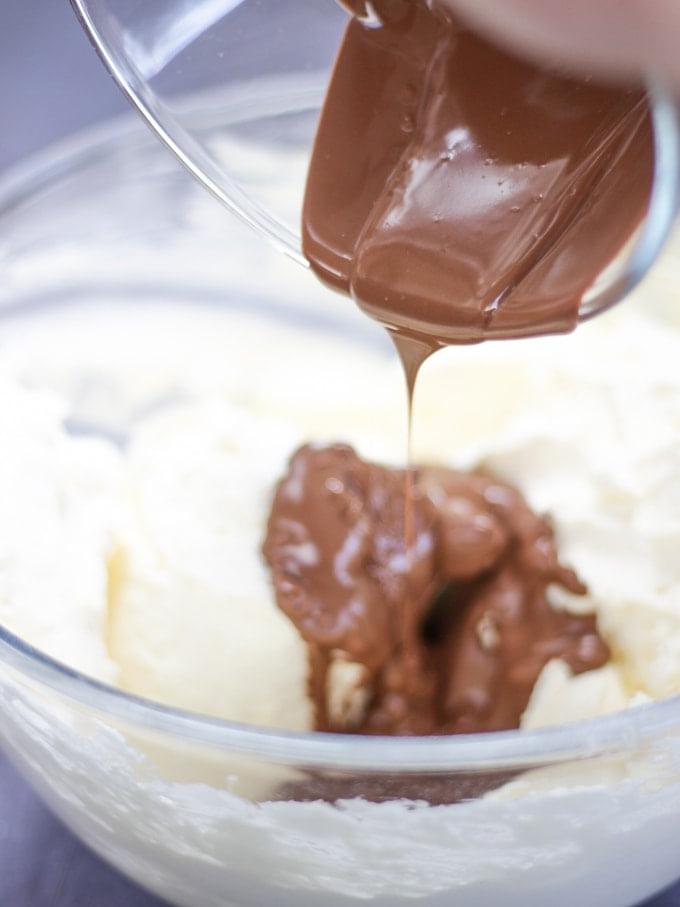 Cheesecake Rocky Road Senza Cottura 5 Una ciotola di vetro con panna montata e cioccolato fuso all'interno per il passaggio 2 della ricetta della Cheesecake Rocky Road.