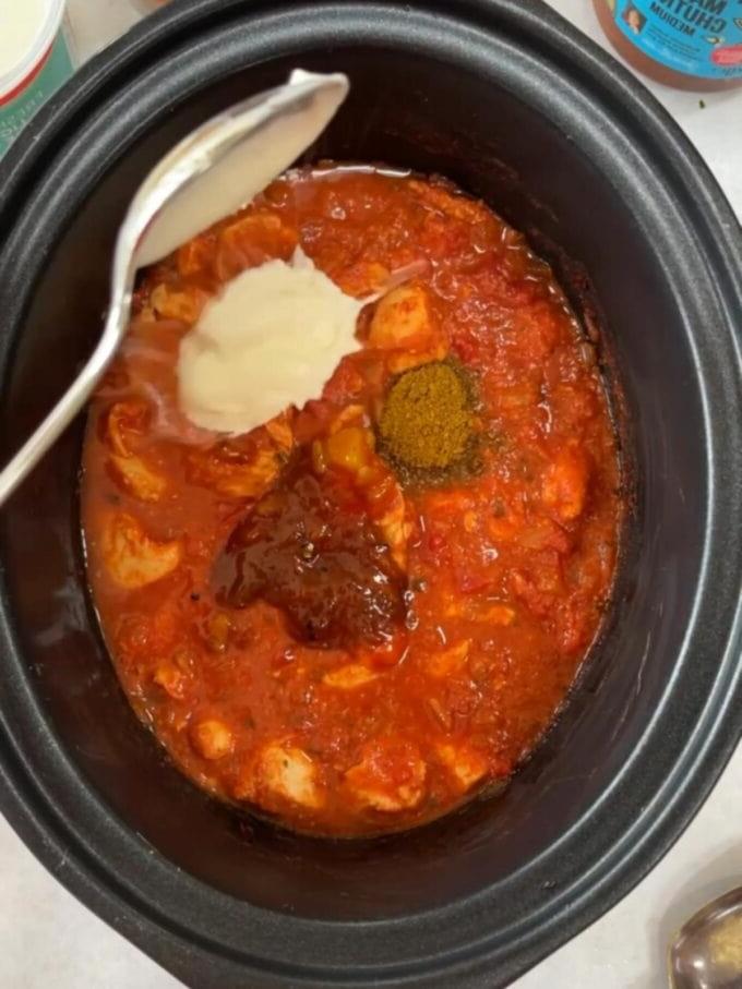 Passo 2 della ricetta per pollo tikka masala in slow cooker con salsa e spezie che vengono aggiunte.