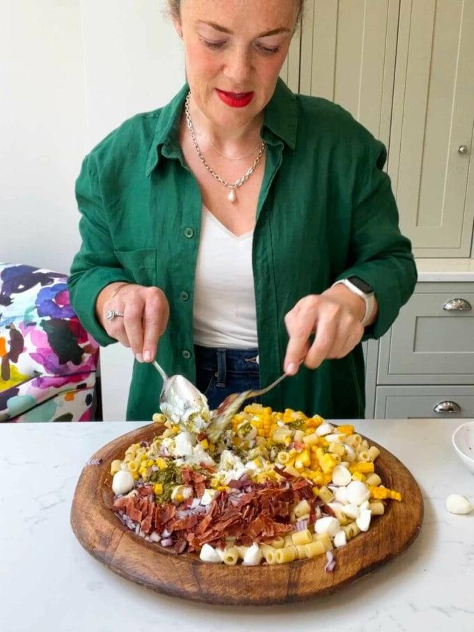 La Migliore Insalata di Pasta al Pesto di Sempre {Pronta in 15 Minuti} 6 Sarah Rossi di Taming Twins che mescola una ricetta per l'insalata di pasta al pesto.
