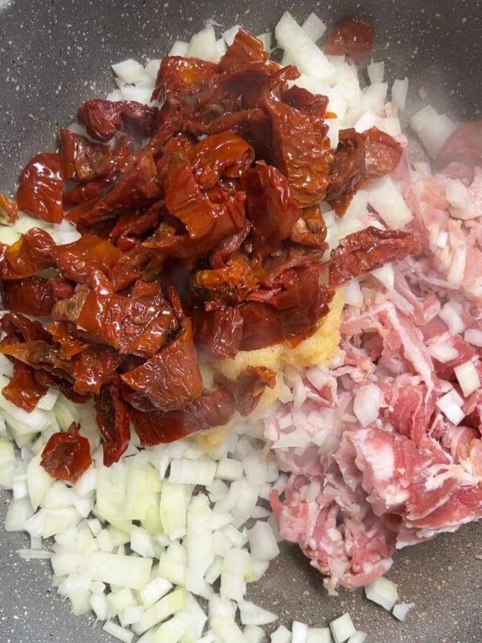 Pomodori secchi in una padella con cipolla e pancetta per la ricetta della Pasta con Pancetta. Passaggio 2.