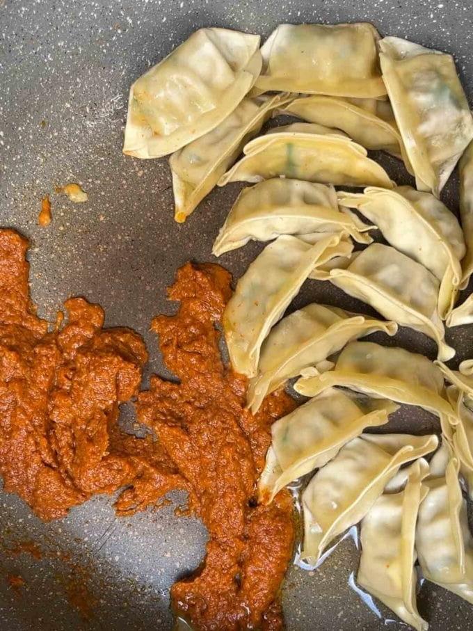 Ravioli e pasta di curry thailandese che friggono in una padella per il passaggio 2 della ricetta della Zuppa di Gyoza.