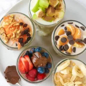 Domenica di Preparazione: Pasti per la Settimana 3 6 Quattro vasetti di avena notturna con diversi topping visti dall'alto.