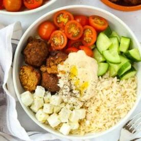Ricette in 15 minuti {Settimana 4} 6 Una ciotola bianca piena di insalata Hummus Bowl, con riso, falafel, hummus, pomodori e cetrioli.