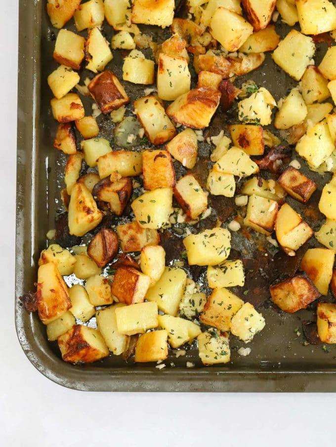 Patate Parmentier all'aglio e alle erbe aromatiche 6 Cubetti di patate cotte e dorate su una teglia, passaggio 2 della ricetta delle patate Parmentier.