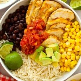 Pasti in 15 minuti {Settimana 3} 6 Una grande ciotola piena di pollo, fagioli, riso, salsa, guacamole, lime e mais dolce per la ricetta Burrito Bowls Senza Cottura.