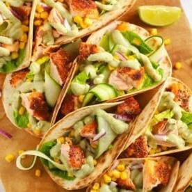 Ricetta facile di tacos di salmone su una tavola di legno con condimento di cetrioli e avocado