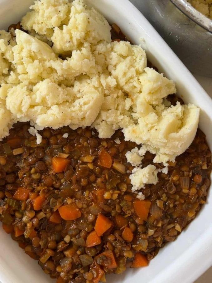 Il Pasticcio Vegetariano Definitivo 7 Fase 3 della ricetta per il Pasticcio Vegetariano. La purea di patate viene aggiunta sopra il ripieno in una teglia.