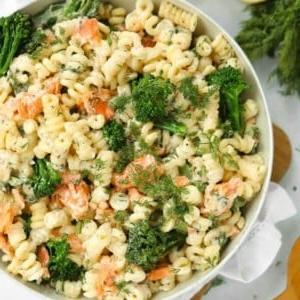 Una grande ciotola piena di pasta al salmone affumicato con broccoli.