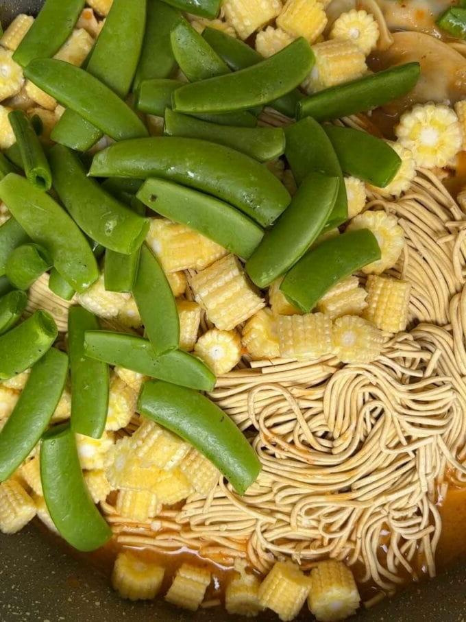 Verdure crude e noodles in una padella per il passaggio 4 della ricetta della Zuppa di Gyoza.