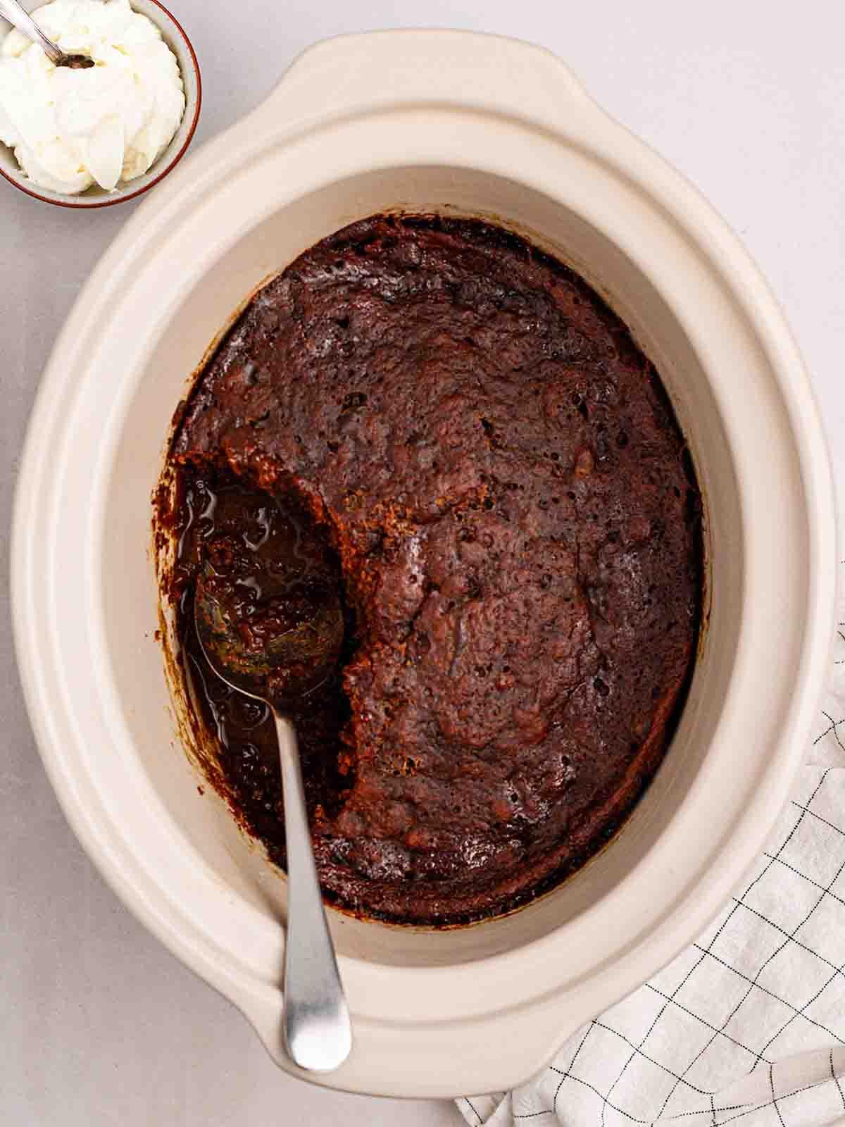 Pudding al Caramello Appiccicoso in Slow Cooker 2 Un slow cooker pieno di budino al toffee appiccicoso, pronto per essere servito con un cucchiaio.