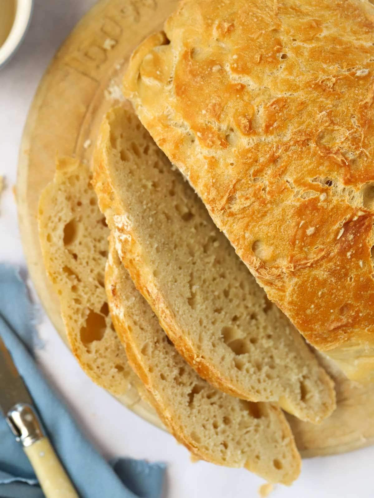 Pane Senza Impasto {La Ricetta Notturna Più Semplice di Sempre} 3 Un filone di pane casalingo senza impasto tagliato su un tagliere.